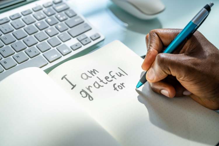 Man writes I am grateful for in notebook