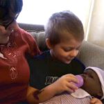 Boy feeding baby doll