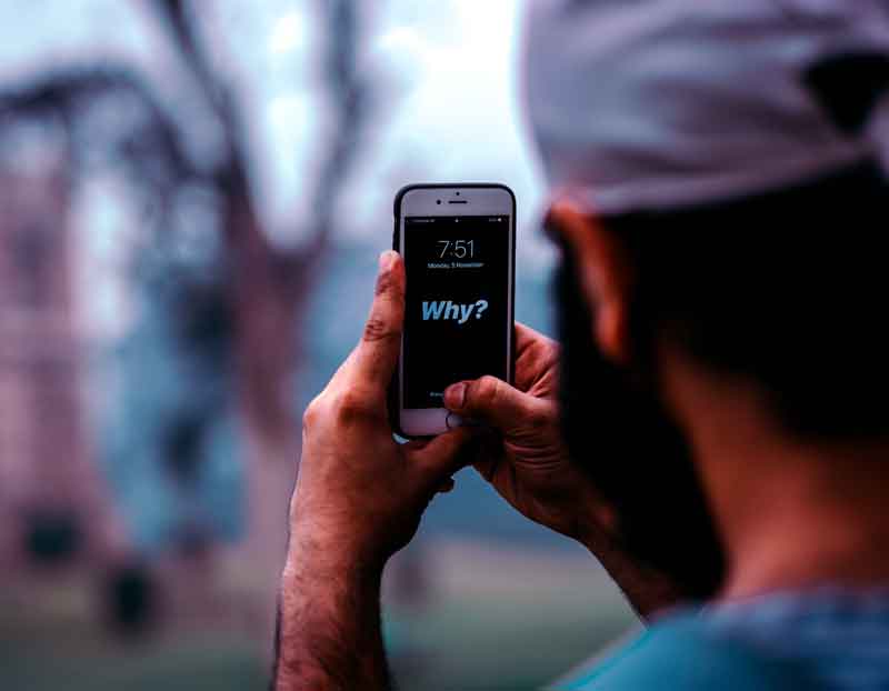 man holding cell phone that read "why?"