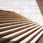 a toddler child stands at the bottom of imposing stone staircase