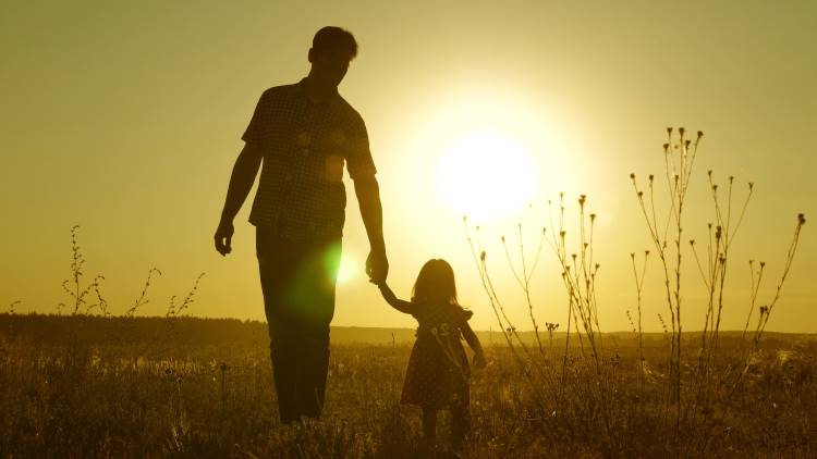 girl dad hold hands in sunset