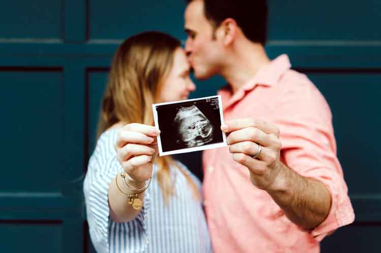 mom and dad to be hold ultrasound of baby