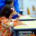 preschool student at school desk writes