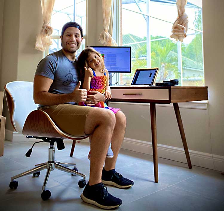 Marlon Gutierrez and his daughter at his remote work station where he works from home in Florida.