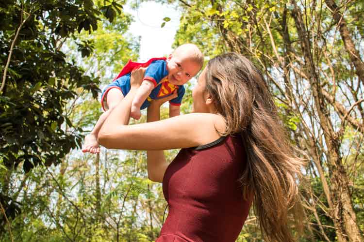 mother playing with baby in superman costume