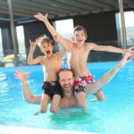 swimming pool dad with kids on shoulders
