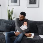 work from home dad with baby laptop on couch